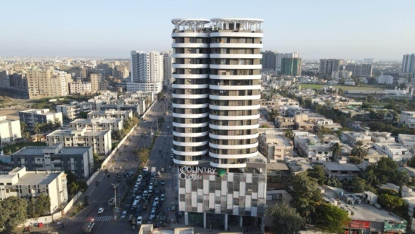 Aerial View Of Country 8 Twin Towers In Clifton Block 8, Modern Curved White High-Rises With Green Base Cladding And Urban Su