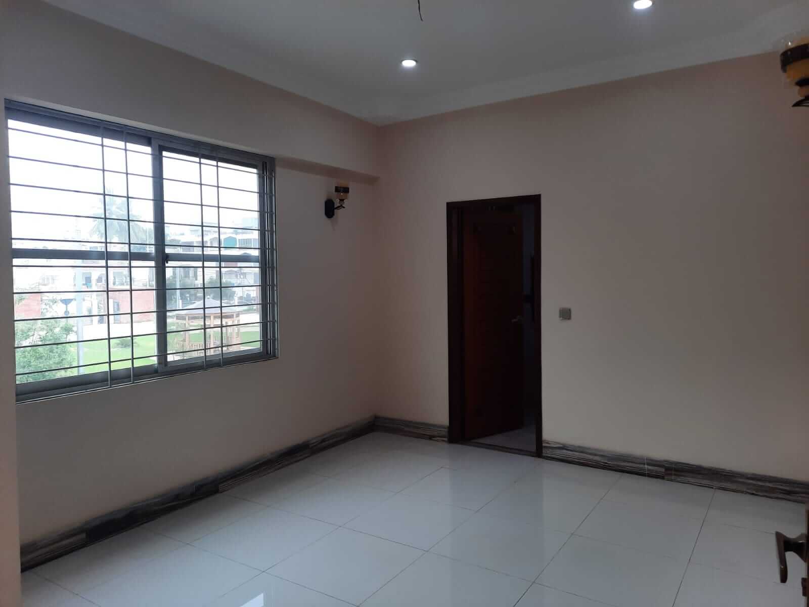 Dunes Marvel 3-Bedroom Apartment for Sale in Clifton Block 5 Karachi (11) Empty room interior in Dunes Marvel 3-bedroom apartment Clifton Block 5 Karachi with large window and white tiled floor