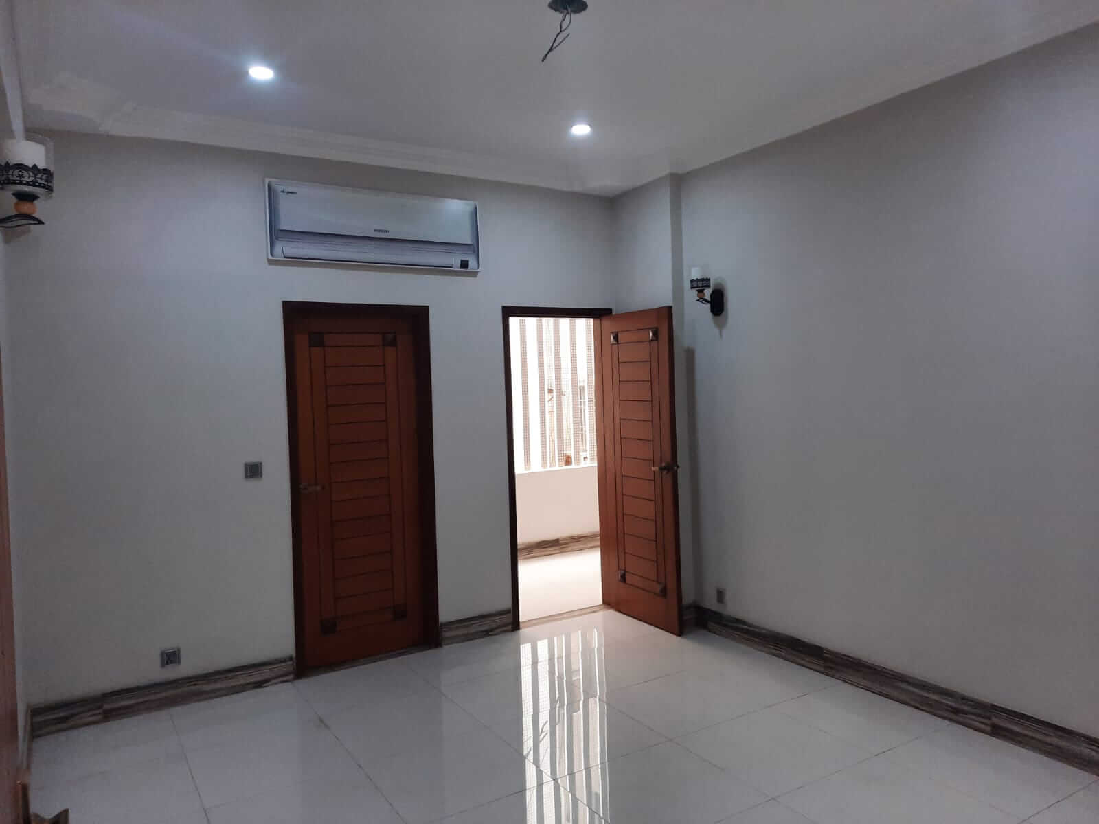Dunes Marvel 3-Bedroom Apartment for Sale in Clifton Block 5 Karachi (13) Empty room in Dunes Marvel 3-bedroom apartment Clifton Block 5 Karachi with white tiled floor wooden doors and air conditione