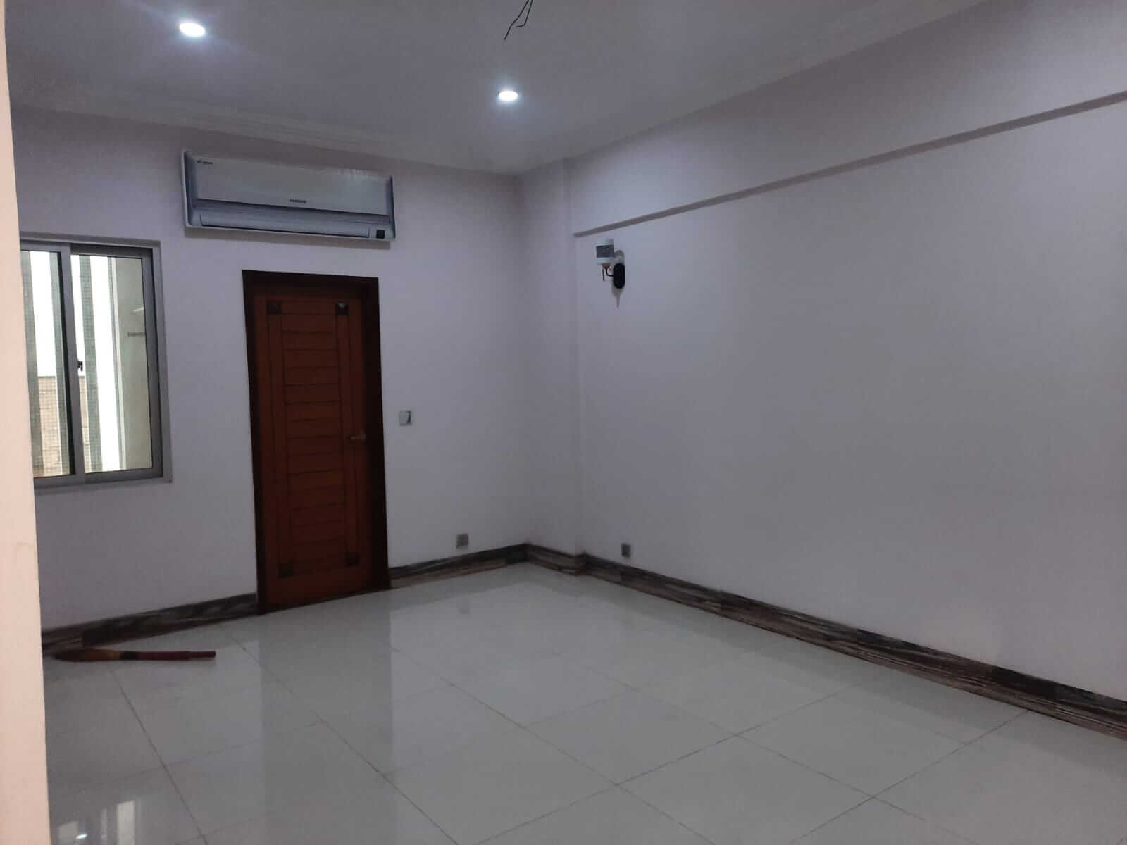 Dunes Marvel 3-Bedroom Apartment for Sale in Clifton Block 5 Karachi (16) Empty room interior in Dunes Marvel 3-Bedroom Apartment Clifton Block 5 Karachi with wooden door window and wall AC unit