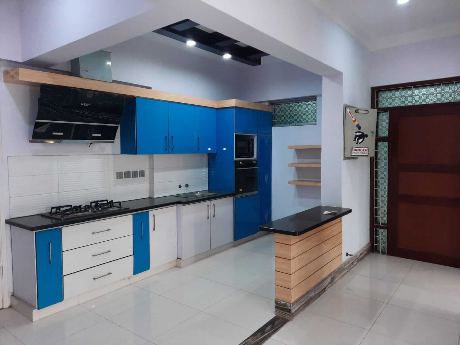 Dunes Marvel 3-Bedroom Apartment for Sale in Clifton Block 5 Karachi (19) Modern kitchen with blue and white cabinets, black countertops and built-in appliances in Dunes Marvel 3-bedroom apartment Cl