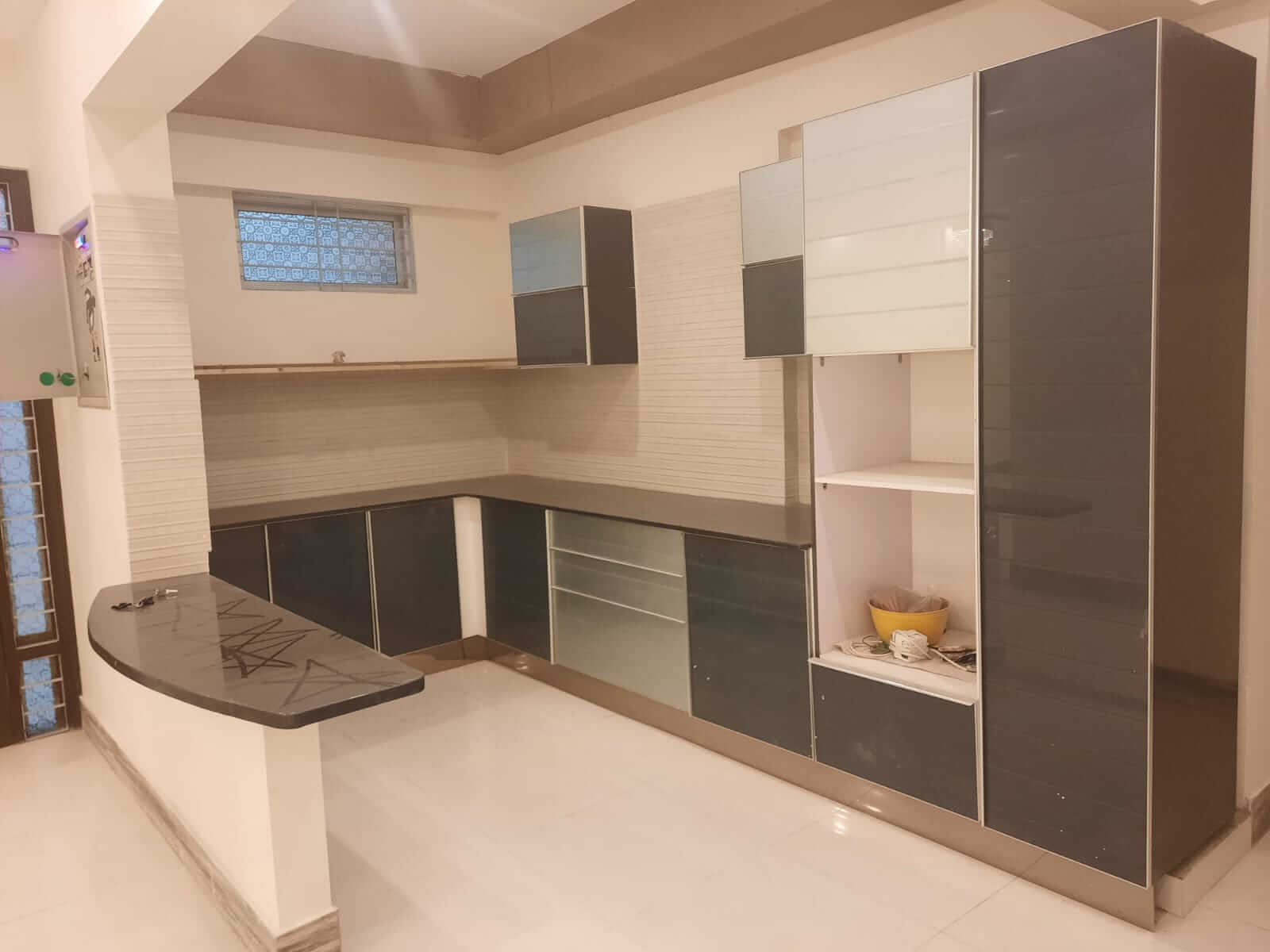 Dunes Marvel Clifton 3-Bedroom Flat for Sale in Clifton Block 5 Karachi (14) Modern L-shaped kitchen with dark glossy cabinets, breakfast bar and open shelving at Dunes Marvel Clifton apartment in Clift