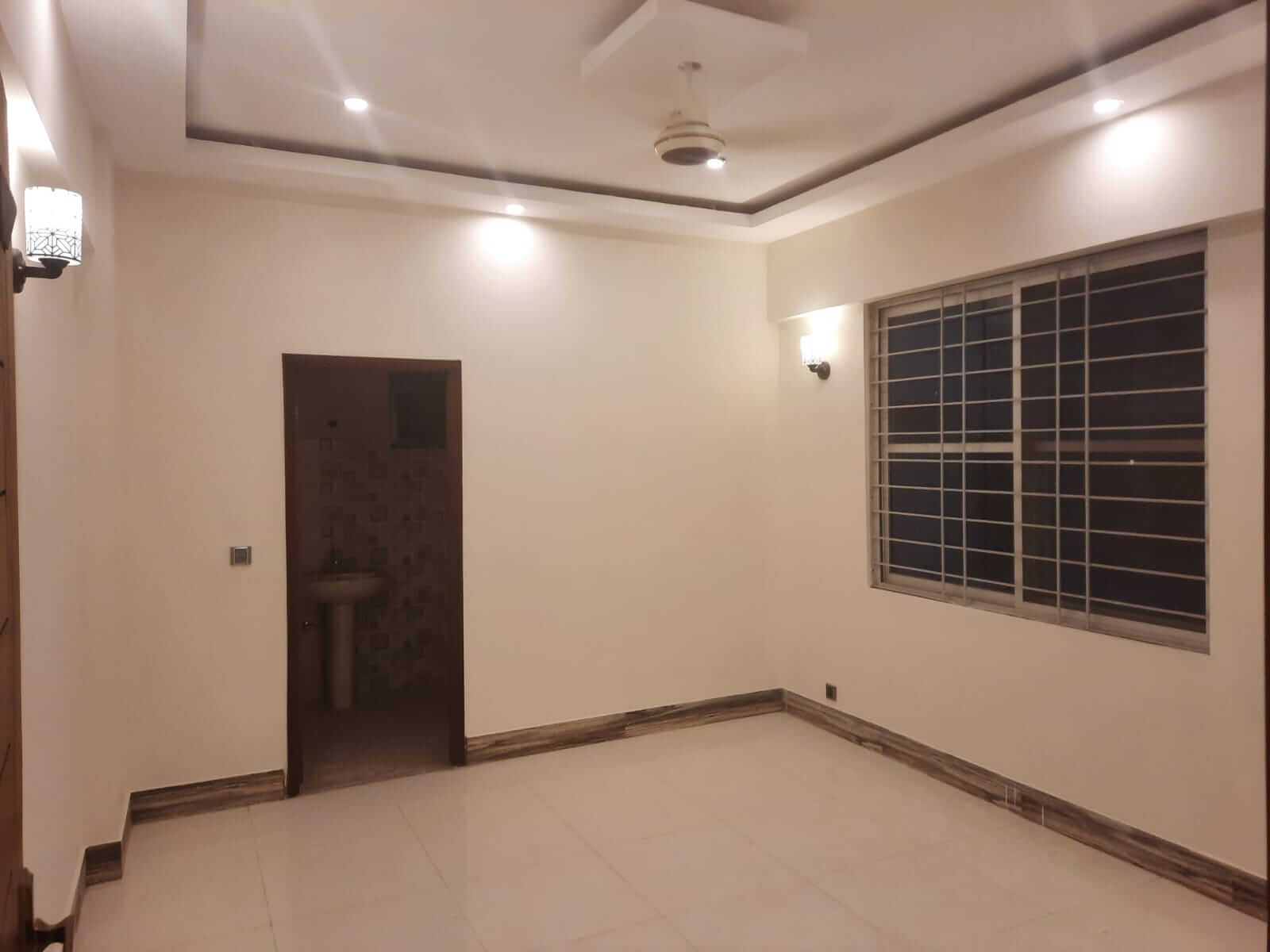 Dunes Marvel Clifton 3-Bedroom Flat for Sale in Clifton Block 5 Karachi (2) Spacious empty room in Dunes Marvel Clifton flat Clifton Block 5 Karachi with large window and bathroom doorway