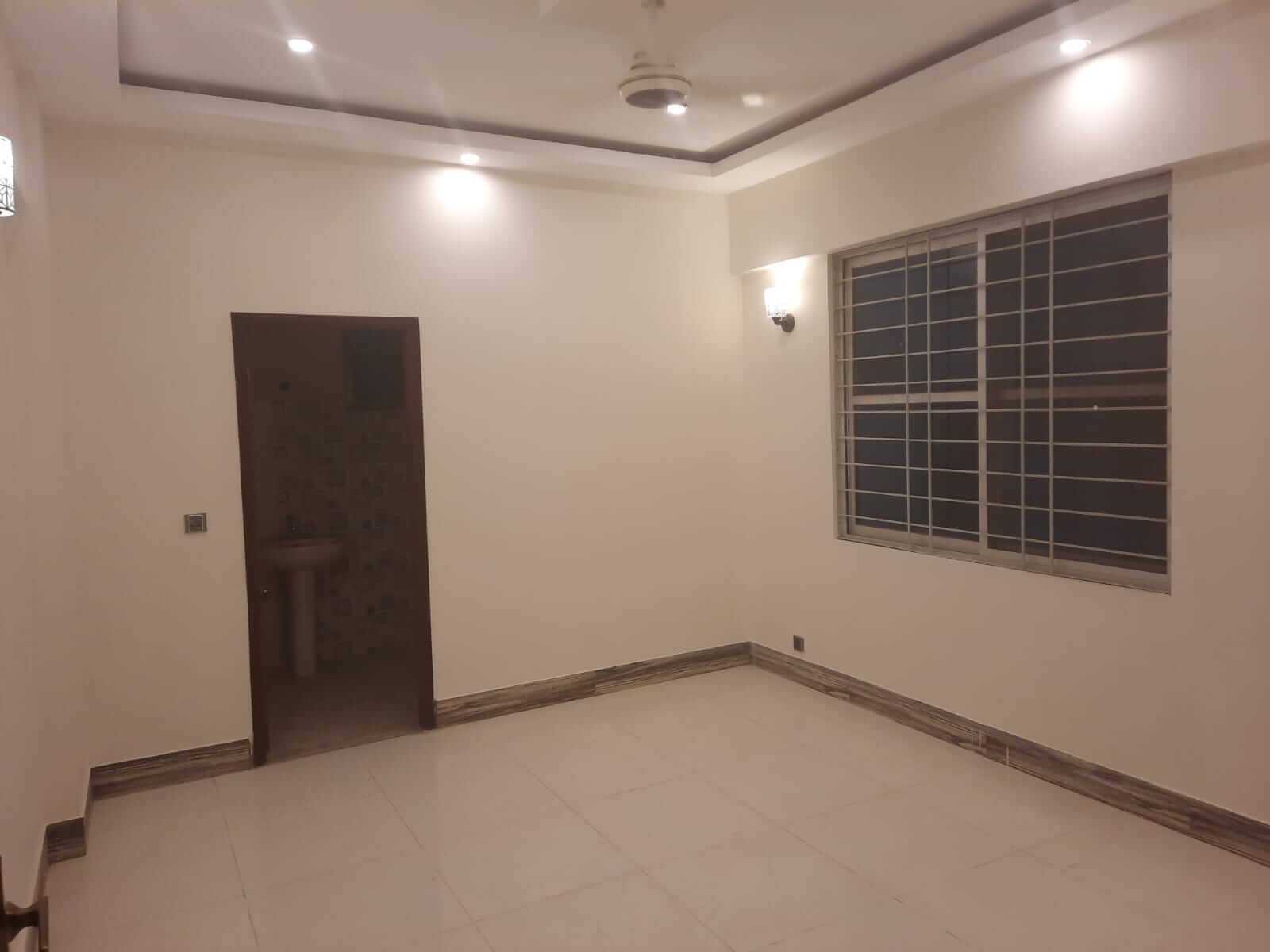 Dunes Marvel Clifton 3-Bedroom Flat for Sale in Clifton Block 5 Karachi (3) Empty bedroom interior at Dunes Marvel Clifton flat, Clifton Block 5 Karachi with large grilled window and attached bathroom