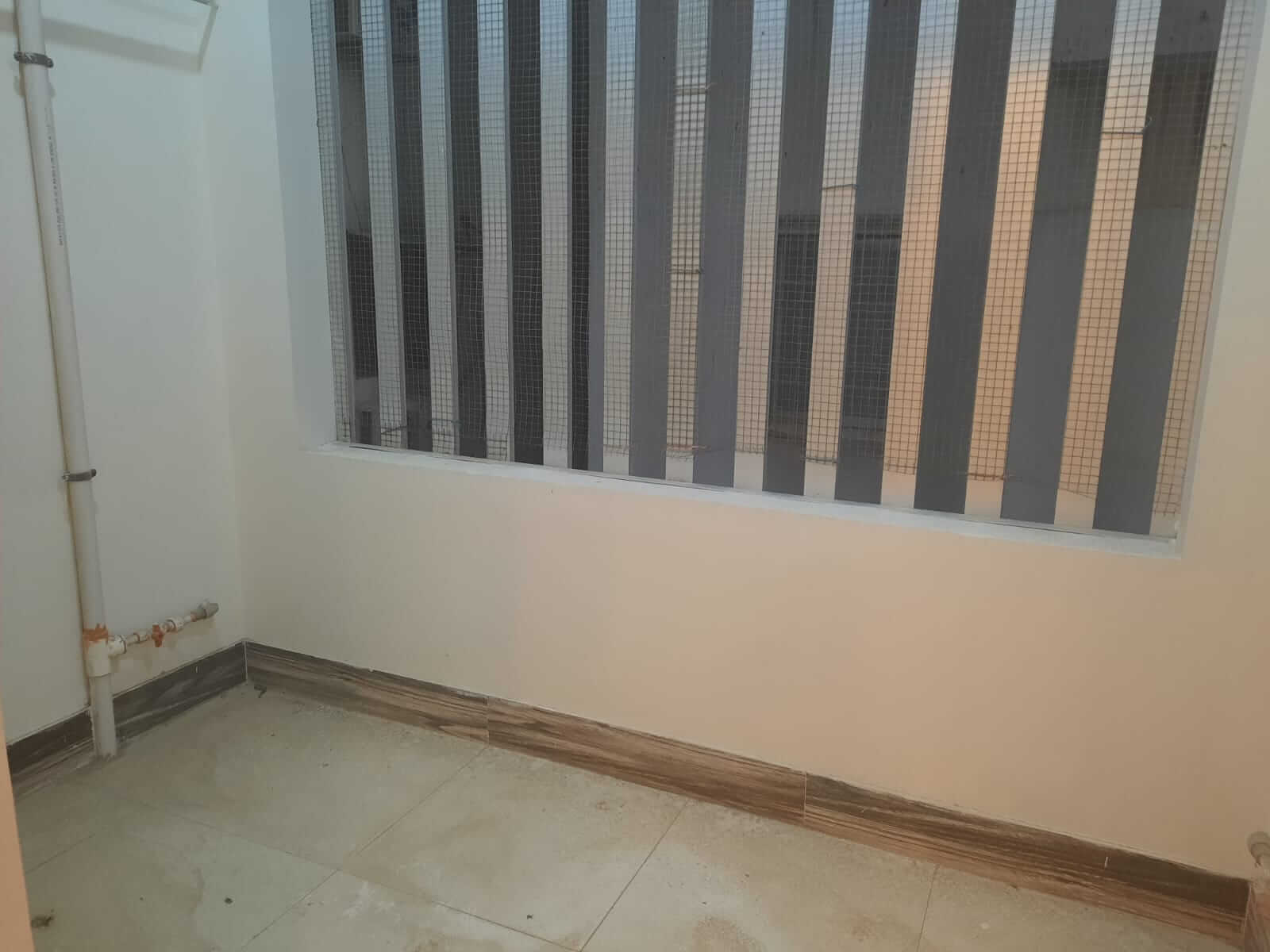 Dunes Marvel Clifton 3-Bedroom Flat for Sale in Clifton Block 5 Karachi (8) Empty room with tiled floor, white walls and large security grilled window in Dunes Marvel Clifton flat Block 5 Karachi