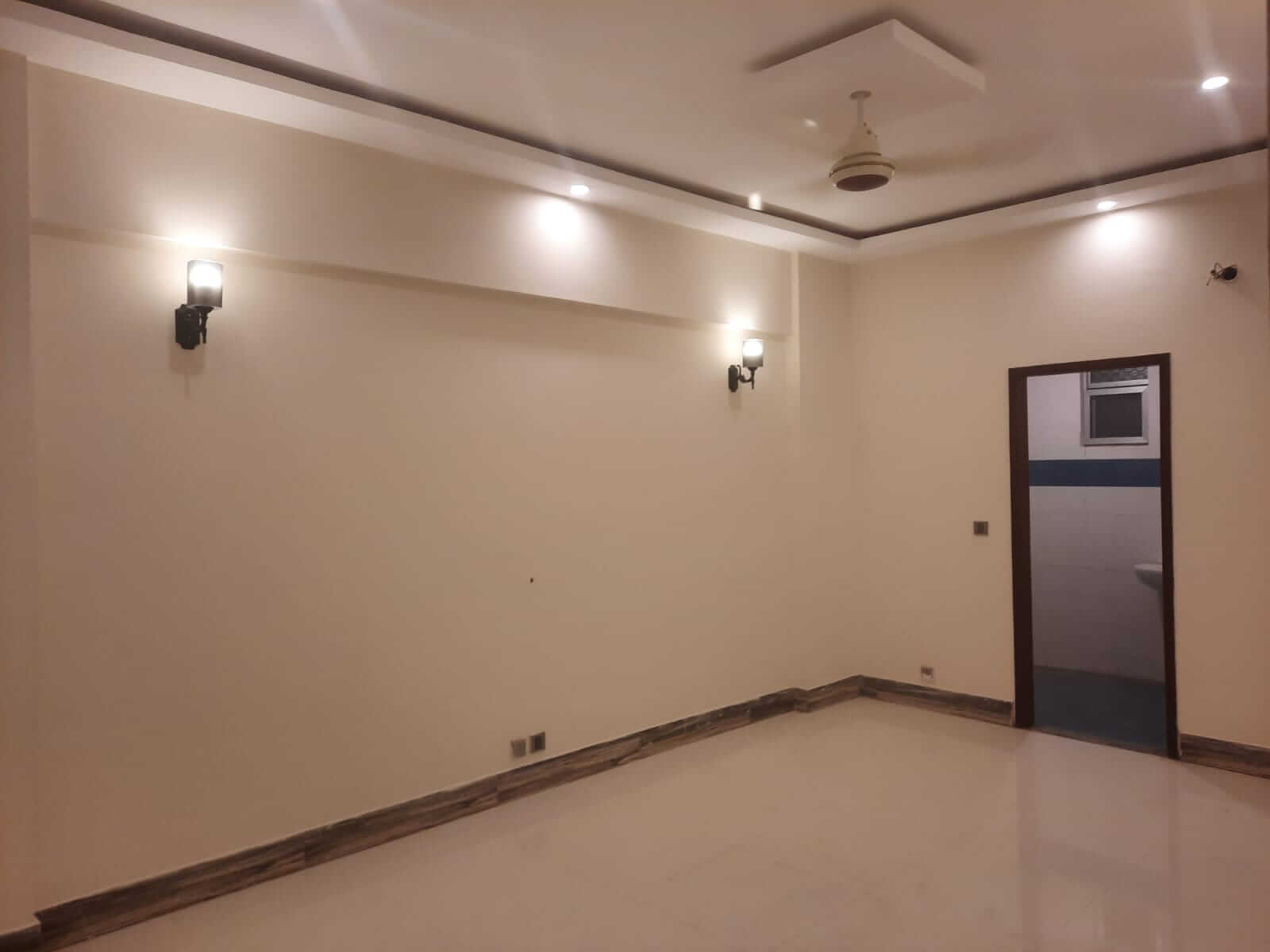 Dunes Marvel Clifton 3-Bedroom Flat for Sale in Clifton Block 5 Karachi (9) Empty room interior at Dunes Marvel Clifton flat in Clifton Block 5 Karachi with ceiling fan wall sconces and tiled floor
