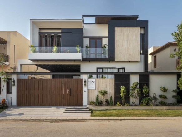 Modern Two-Story House In Dha Phase 8 Karachi With White And Black Facade, Wooden Double Gate, Glass Balcony With Plants, Lan