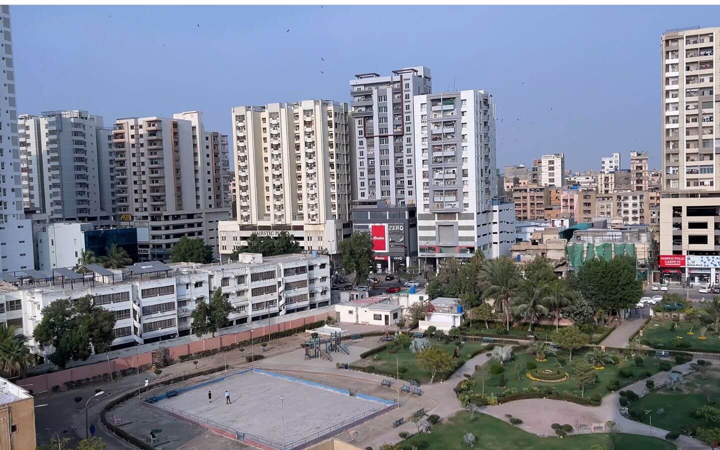 4 Bed DD Apartment for Sale in Zamzam Parkview, Clifton Block 8 – Park Facing at PKR 7.55 Crore (2) Park-facing view of Zamzam Parkview in Clifton Block 8 showing high-rise apartments, green park with palm trees, benches, pat