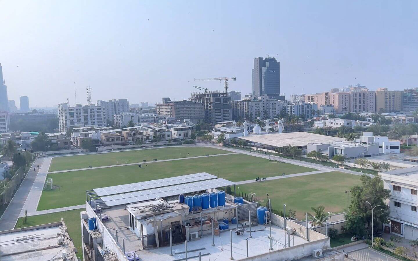 4 Bed DD Apartment for Sale in Zamzam Parkview, Clifton Block 8 – Park Facing at PKR 7.55 Crore (3) Park-facing aerial view of expansive green field with pathways, surrounded by apartments and construction cranes in Zamzam Pa