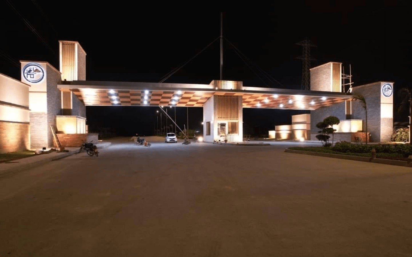 Illuminated main entrance gate of Askari 6 Karachi with modern pillars, bridge structure and Askari logos at night