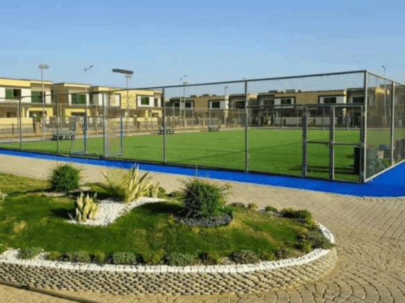 Tennis Court With Green Artificial Turf, Blue Borders, Chain-Link Fencing, Surrounded By Modern Askari Villas In Karachi