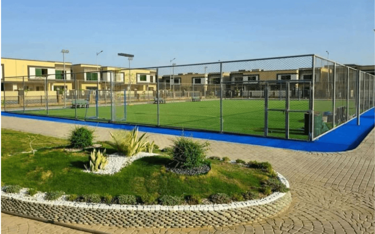 Tennis Court With Green Artificial Turf, Blue Borders, Chain-Link Fencing, Surrounded By Modern Askari Villas In Karachi