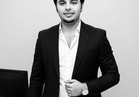 Professional Man In A Suit Standing By An Office Desk In A Modern Workspace