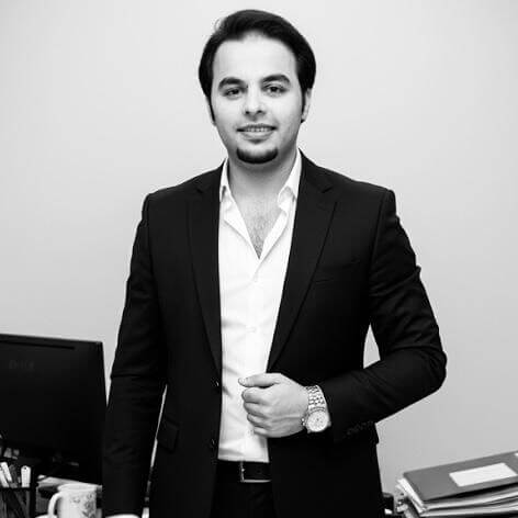 Professional Man In A Suit Standing By An Office Desk In A Modern Workspace