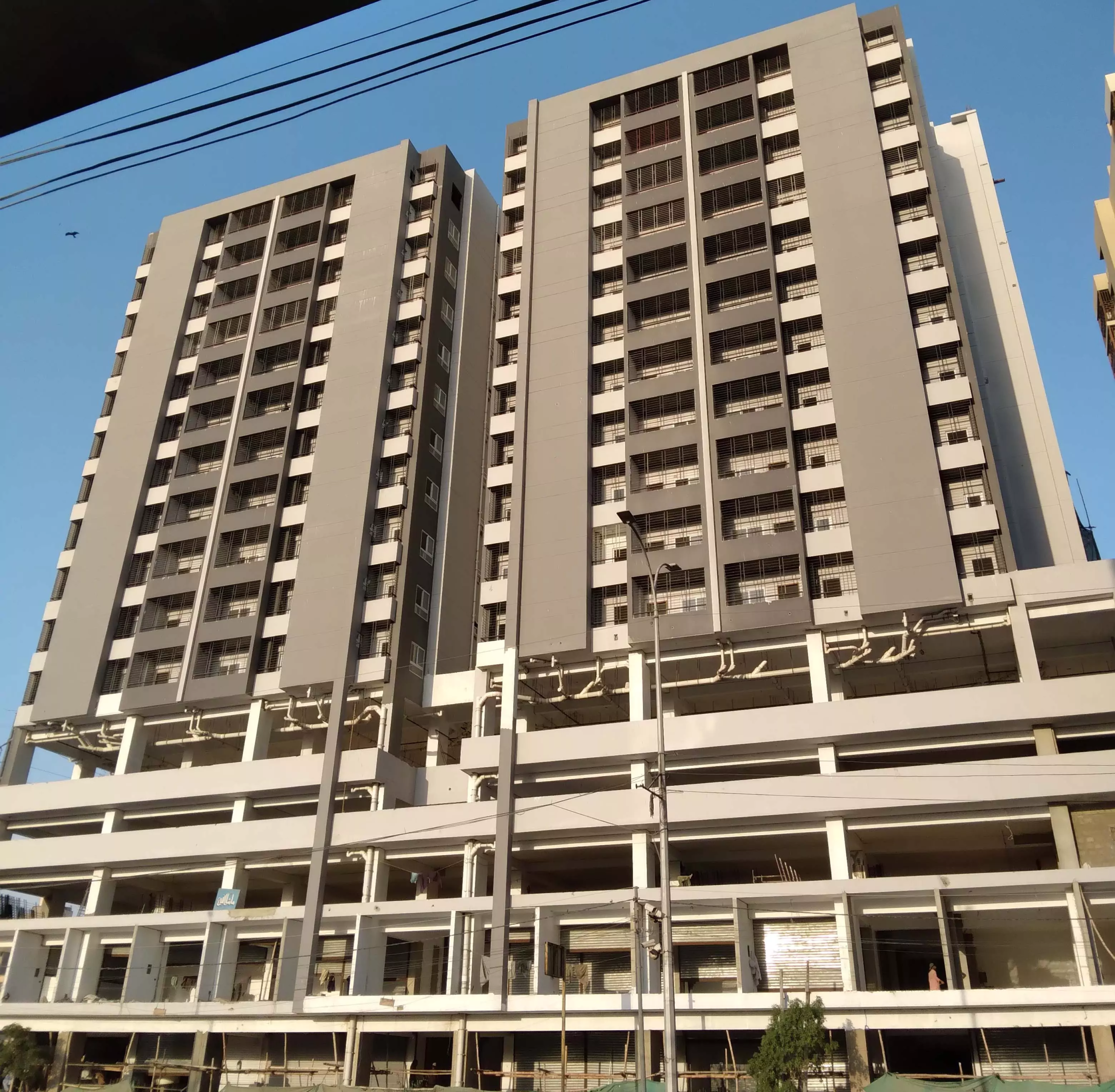 Luxurious 2 Bedroom Flat for Rent in Metro Central Plaza, Clifton Karachi Twin high-rise towers of Metro Central Plaza with grey facades, balconies on multiple floors, and ground-level parking struct