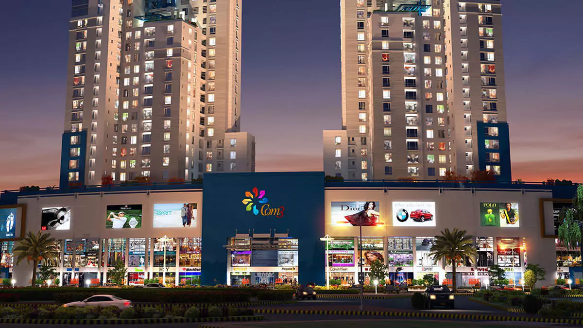 Luxury Living 4 Bedrooms Flat for Rent In COM3 Tower Clifton Block 6 Karachi (4) COM3 Tower in Clifton at dusk, twin high-rise towers with illuminated windows, commercial podium featuring shops, billboards