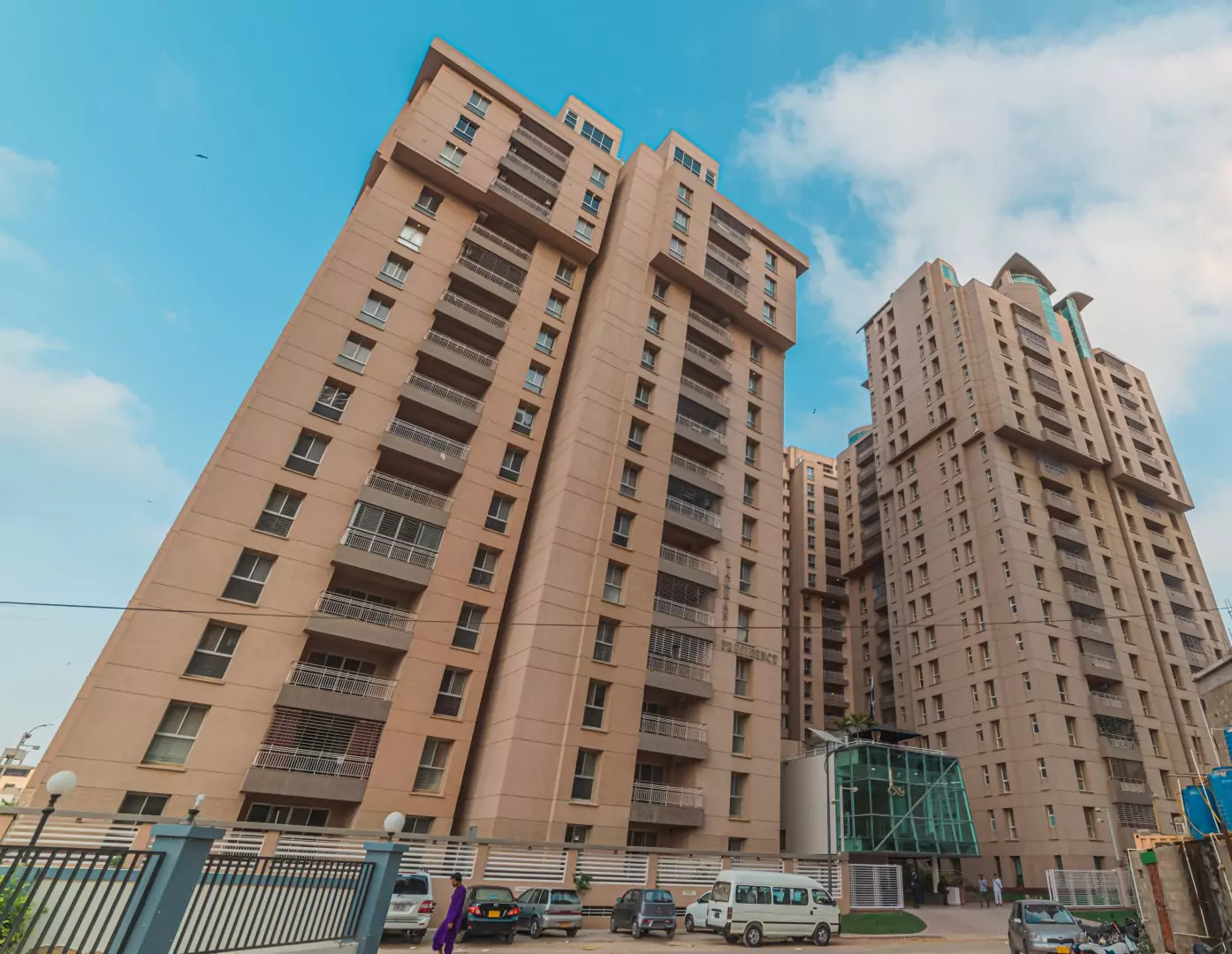 Luxury Flats & Penthouses For Sale in Lakhani Presidency (1) Lakhani Presidency towers in Karachi: tall beige high-rises with balconies, green entrance, gated parking area