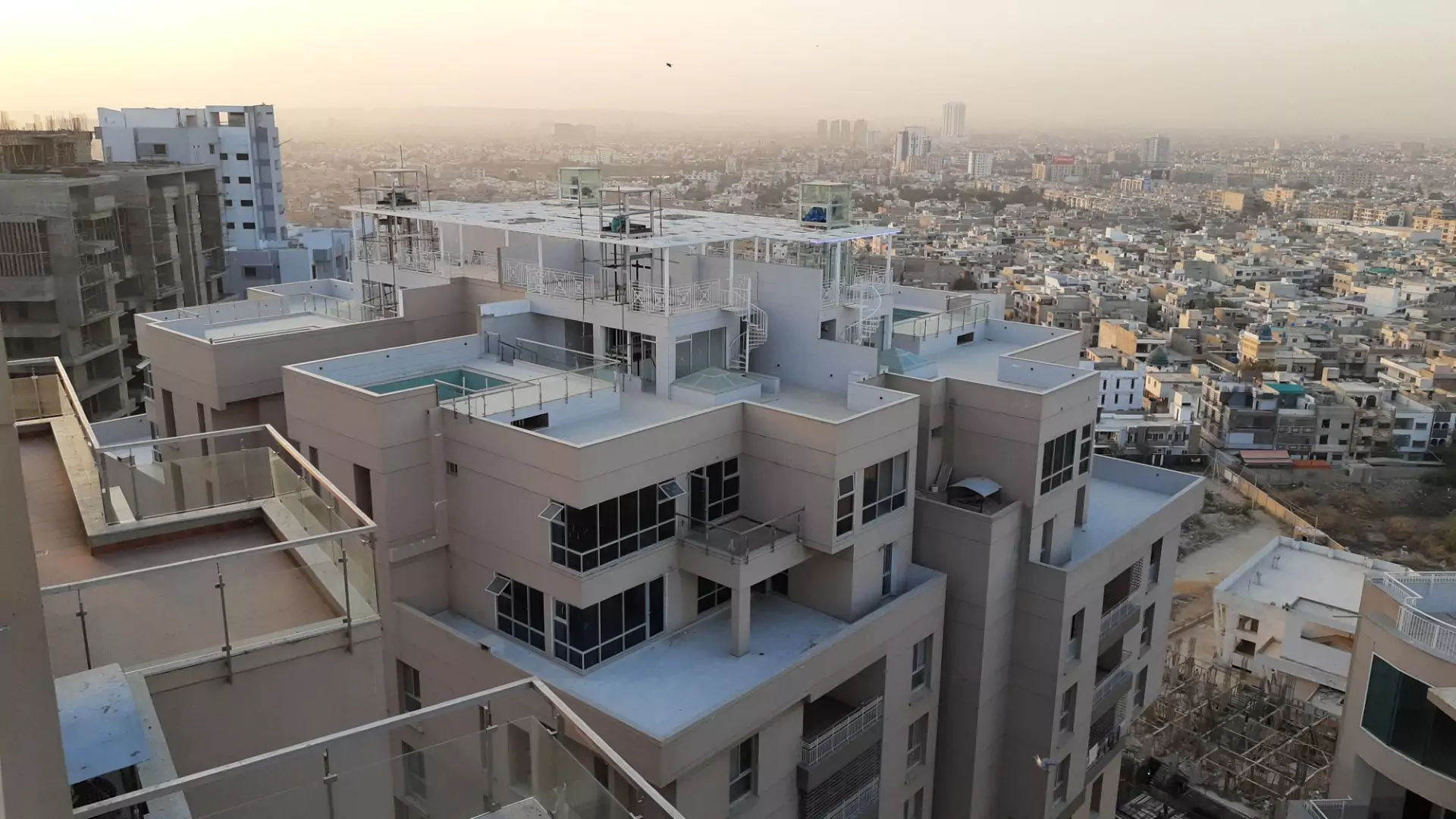 Luxury Flats & Penthouses For Sale in Lakhani Presidency (3) Aerial view of Lakhani Presidency in Karachi showing modern multi-story building with terraced penthouses, glass balconies, r