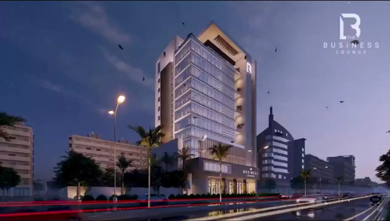 Prime Commercial Spaces for Sale in Gulshan-e-Iqbal, Karachi The Business Lounge (6) Modern glass facade of The Business Lounge commercial office building at dusk with palm trees, street lights, and urban surro