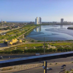 Clifton Marina High-Rise In Karachi Clifton With Modern Grey Facade, Balconies, Signage, Street-Level Entrance And Vehicles