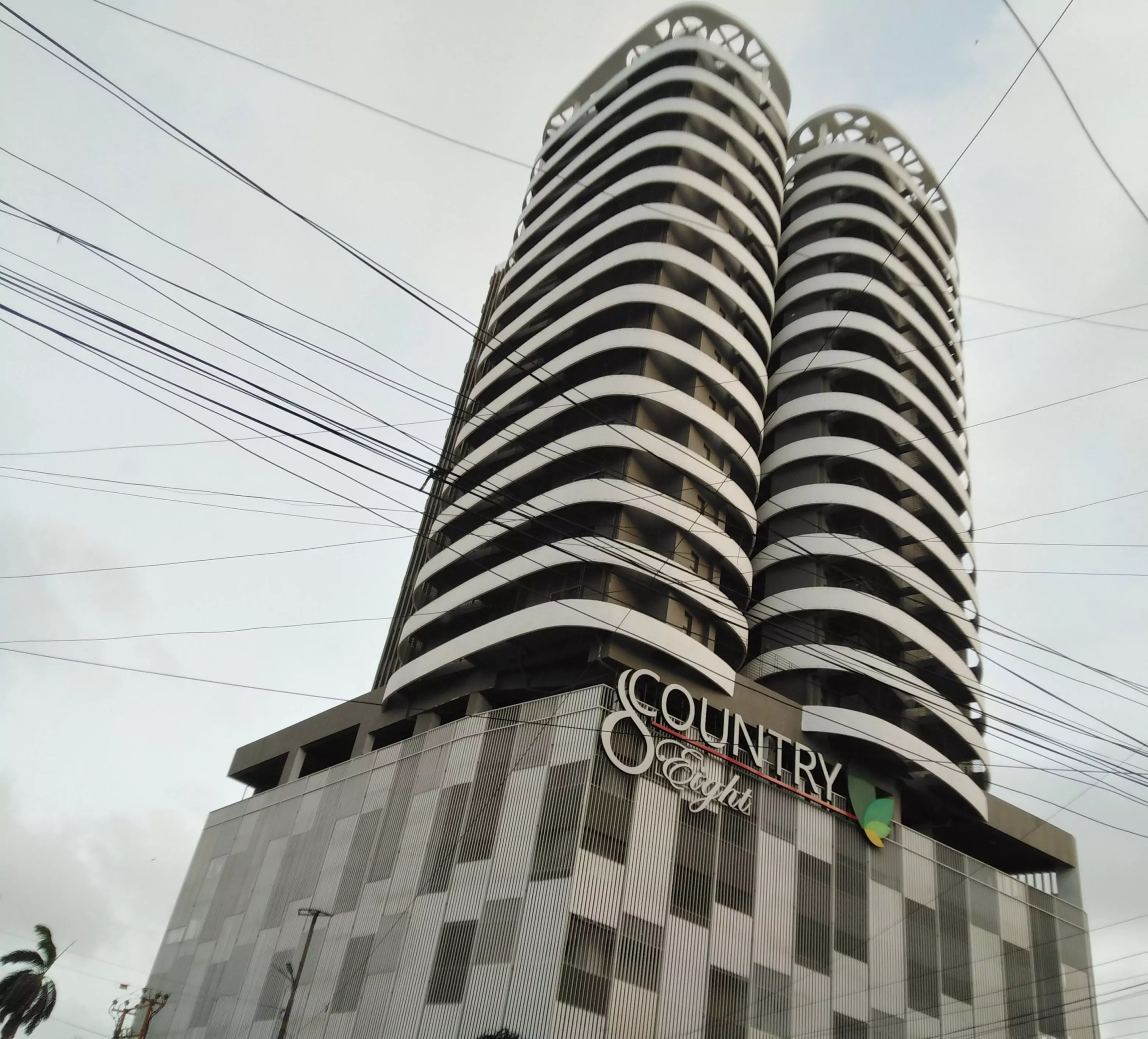 Country 8 Luxury 3 Bedroom Flat For Sale in Block 8 Khaliq-uz-zaman Road Clifton (4) Modern curved high-rise towers of Country 8 in Clifton Block 8, white and dark striped facade, base panels, trees and streetl