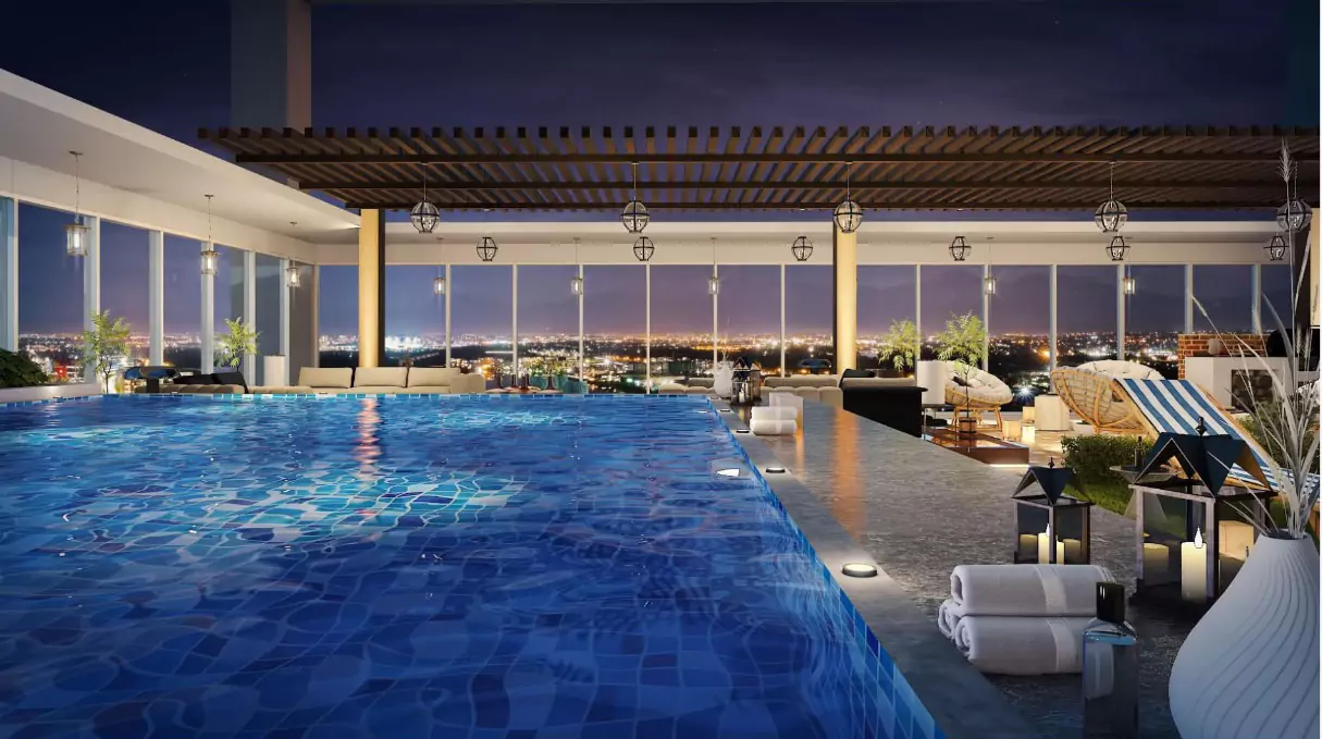 Askari Towers Karachi 3-4 Bedrooms Luxury Apartments For Sale in Cantt Near Jinnah Hosital (7) Rooftop infinity pool with lounge seating, plants, and city skyline view at night in Askari Towers Karachi Cantt