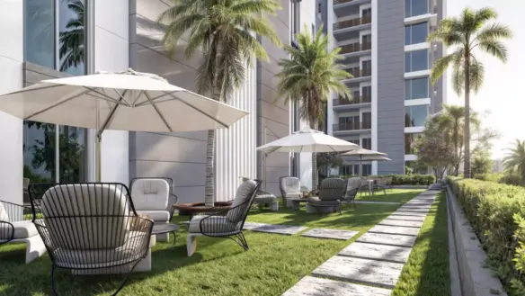 Outdoor lounge with lounge chairs, umbrellas, palm trees and modern tower facade at Saima Shield Towers in Gulshan-e-Iqbal