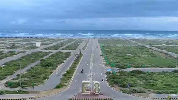 Aerial View Of Wide Road Entering E8 Block With Empty Residential Plots, Greenery, Streetlights In Dha Phase 8 Karachi, Sea I
