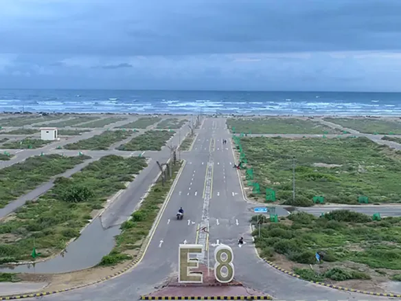 Aerial View Of Wide Road Entering E8 Block With Empty Residential Plots, Greenery, Streetlights In Dha Phase 8 Karachi, Sea I