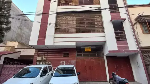 Ground Floor Portion For Sale In North Nazimabad Block C, Modern White House With Maroon Accents, Gated Driveway, Two Parked 
