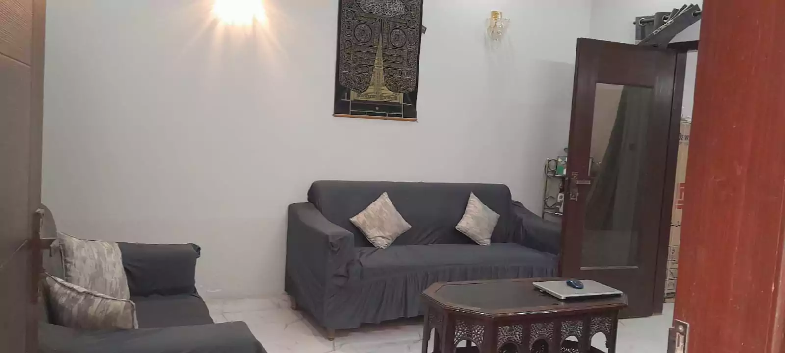 Prime Ground Floor Portion for Sale in North Nazimabad Block C Karachi (4) Living room in ground floor portion for sale North Nazimabad Block C featuring gray sofas, wooden coffee table, wall art, and