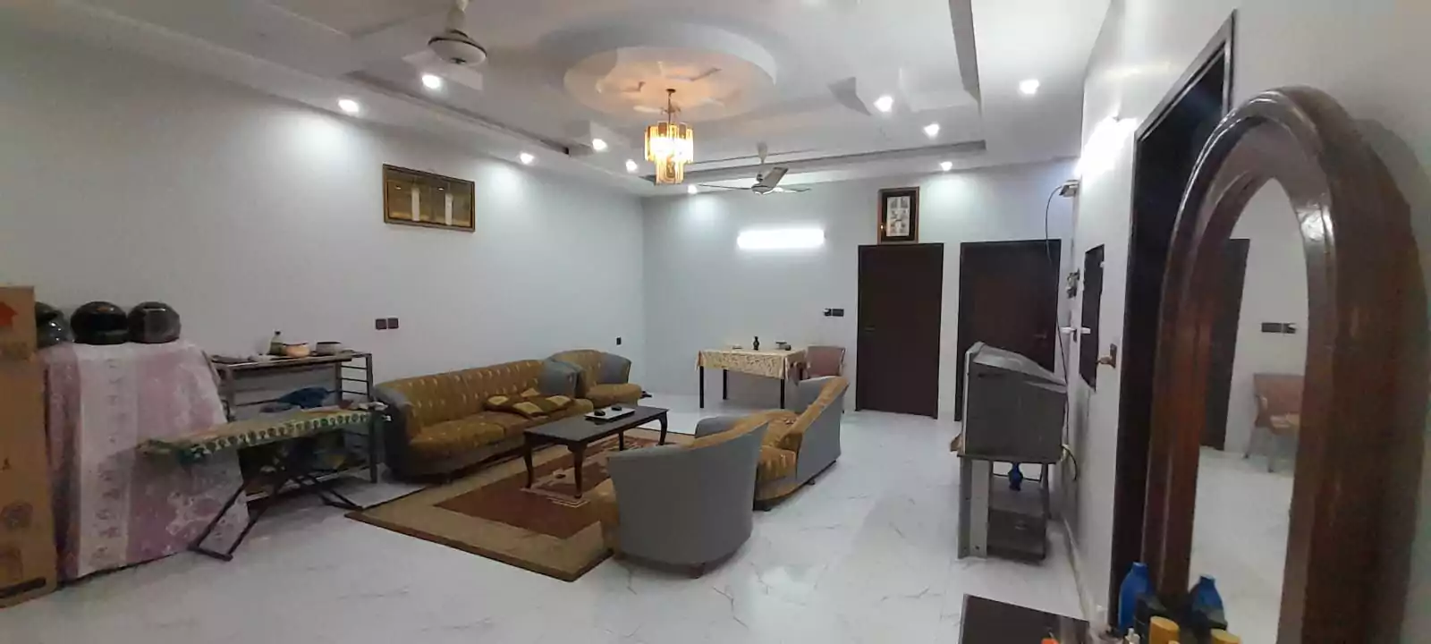 Prime Ground Floor Portion for Sale in North Nazimabad Block C Karachi (8) Spacious living room in ground floor portion, North Nazimabad Block C, with L-shaped grey sofa, armchairs, wooden coffee tabl