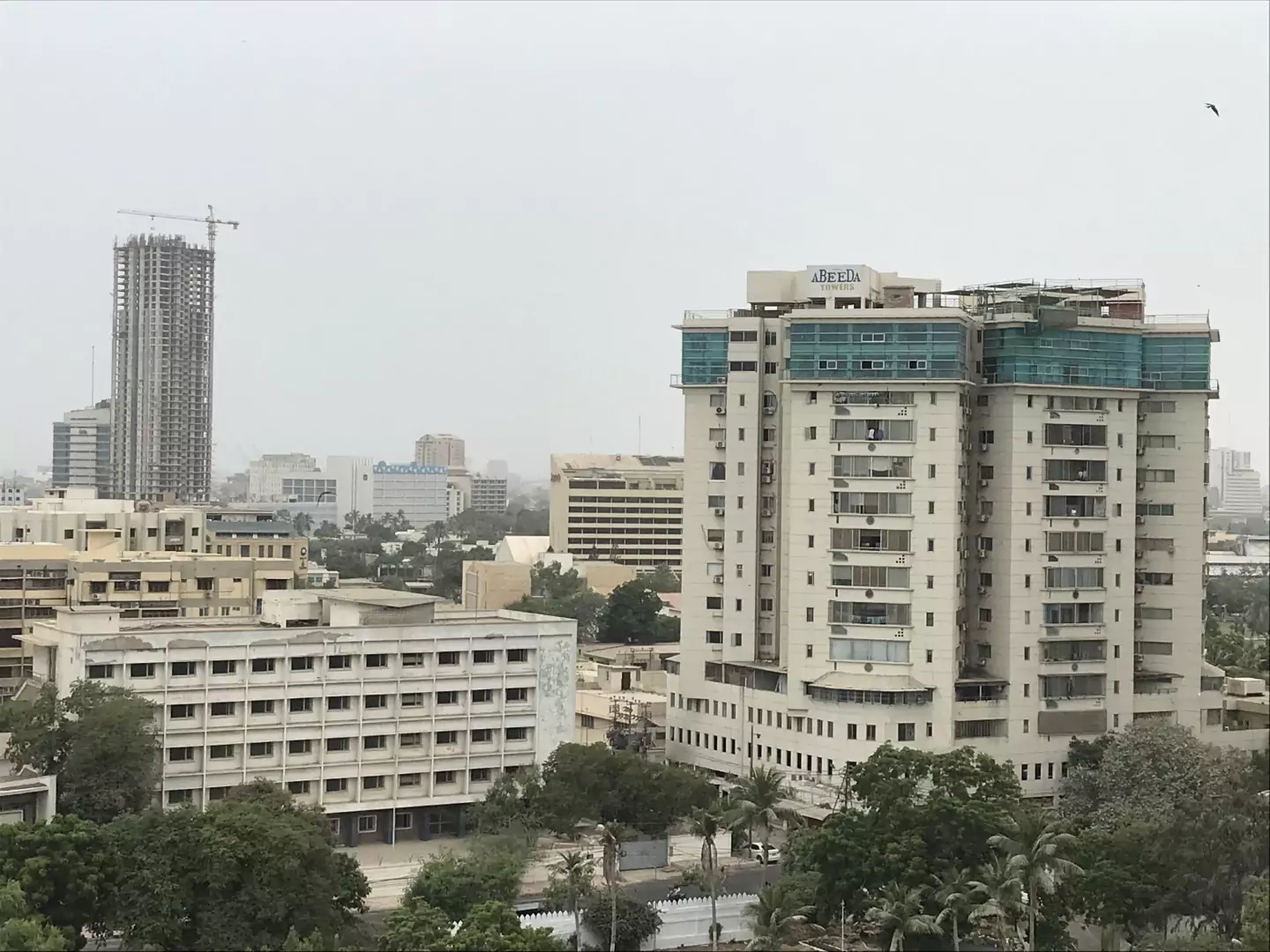 Abeeda Tower 4-Bed Luxury Apartment For Sale in Civil Lines, Karachi (1) Abeeda Tower high-rise in Civil Lines with modern white facade, green glass panels, balconies, and surrounding urban building