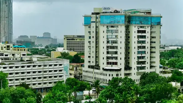 Abeeda Tower Luxury Apartment Building In Civil Lines, Tall White Facade With Blue Accents, Surrounded By Greenery And Urban 
