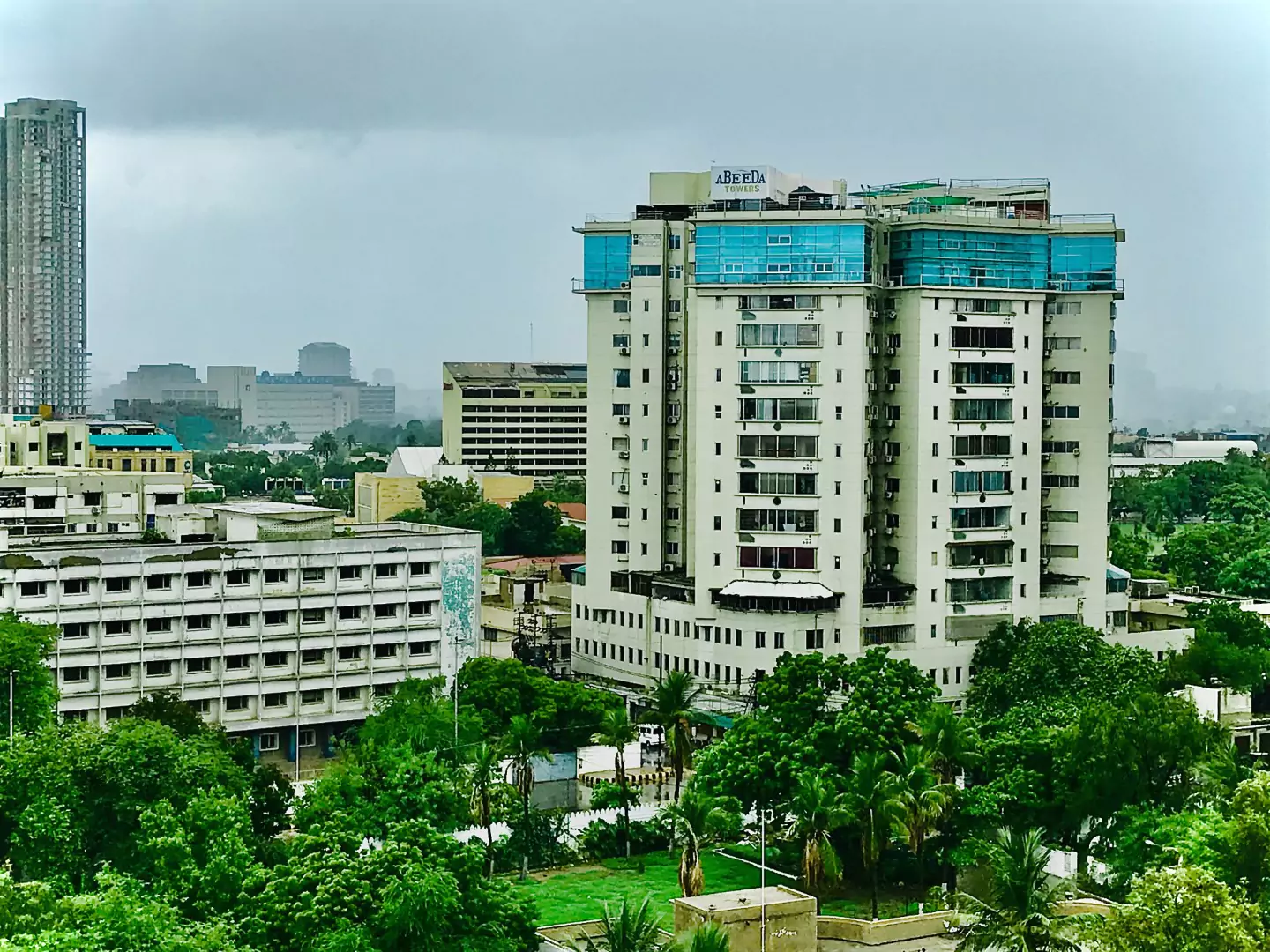 Abeeda Tower 4-Bed Luxury Apartment For Sale in Civil Lines, Karachi (2) Abeeda Tower luxury apartment building in Civil Lines, tall white facade with blue accents, surrounded by greenery and urban