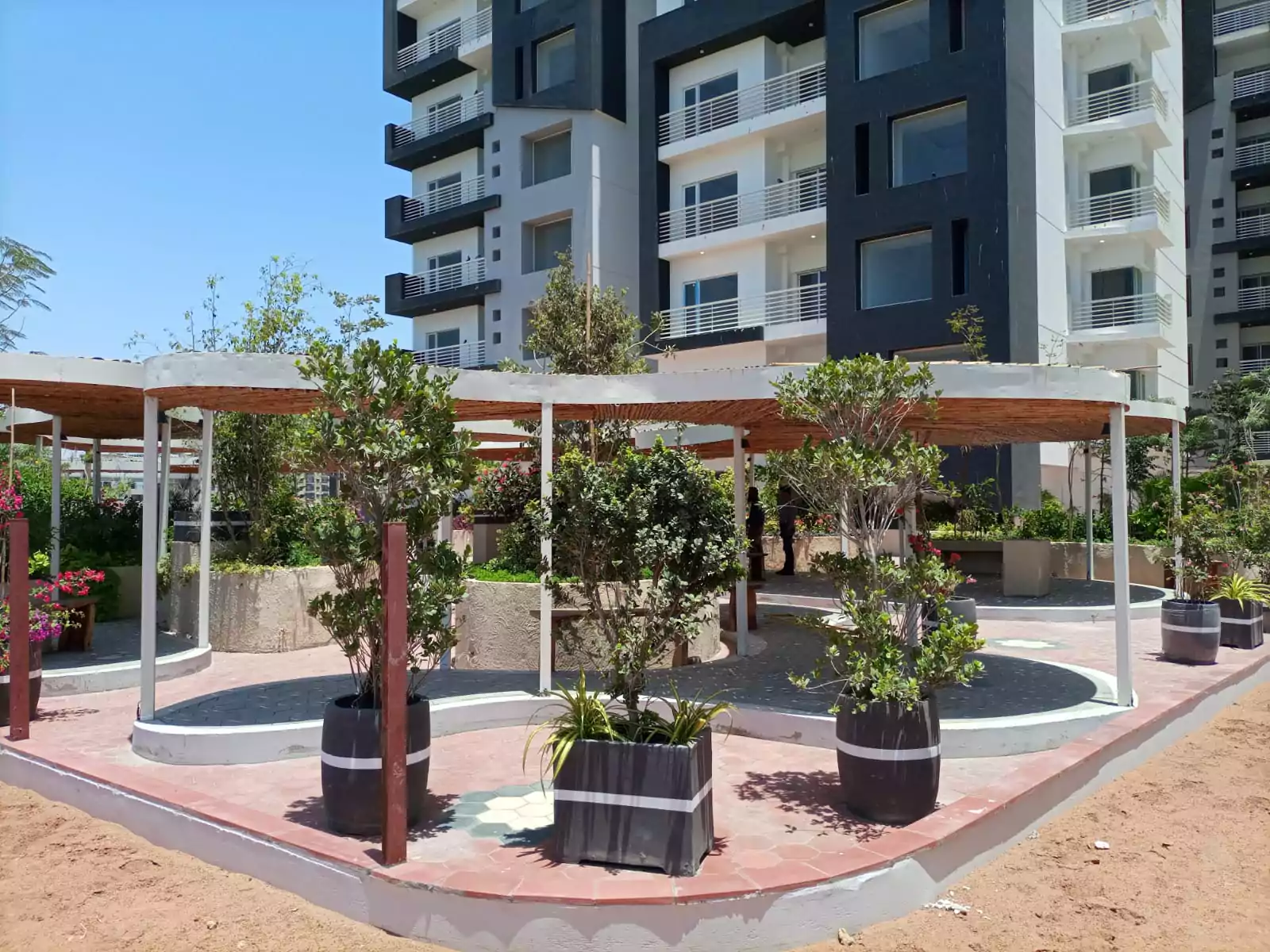 Dynasty Apartments Clifton Luxury 4-Bedroom Flats for Sale in Karachi (1) Landscaped courtyard with shaded pergola, potted plants and trees at Dynasty Apartments Clifton luxury 4-bedroom flats