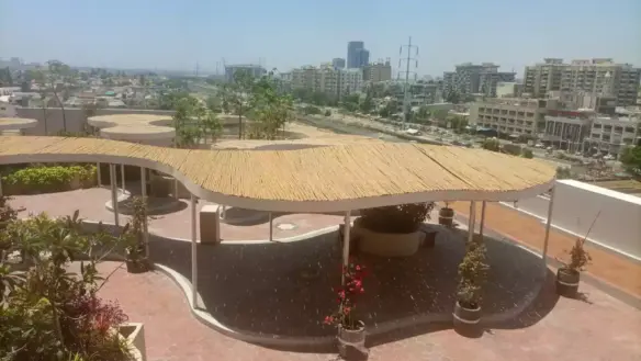 Rooftop terrace with wavy thatched pergola, potted plants and greenery at Dynasty Apartments Clifton, city skyline view