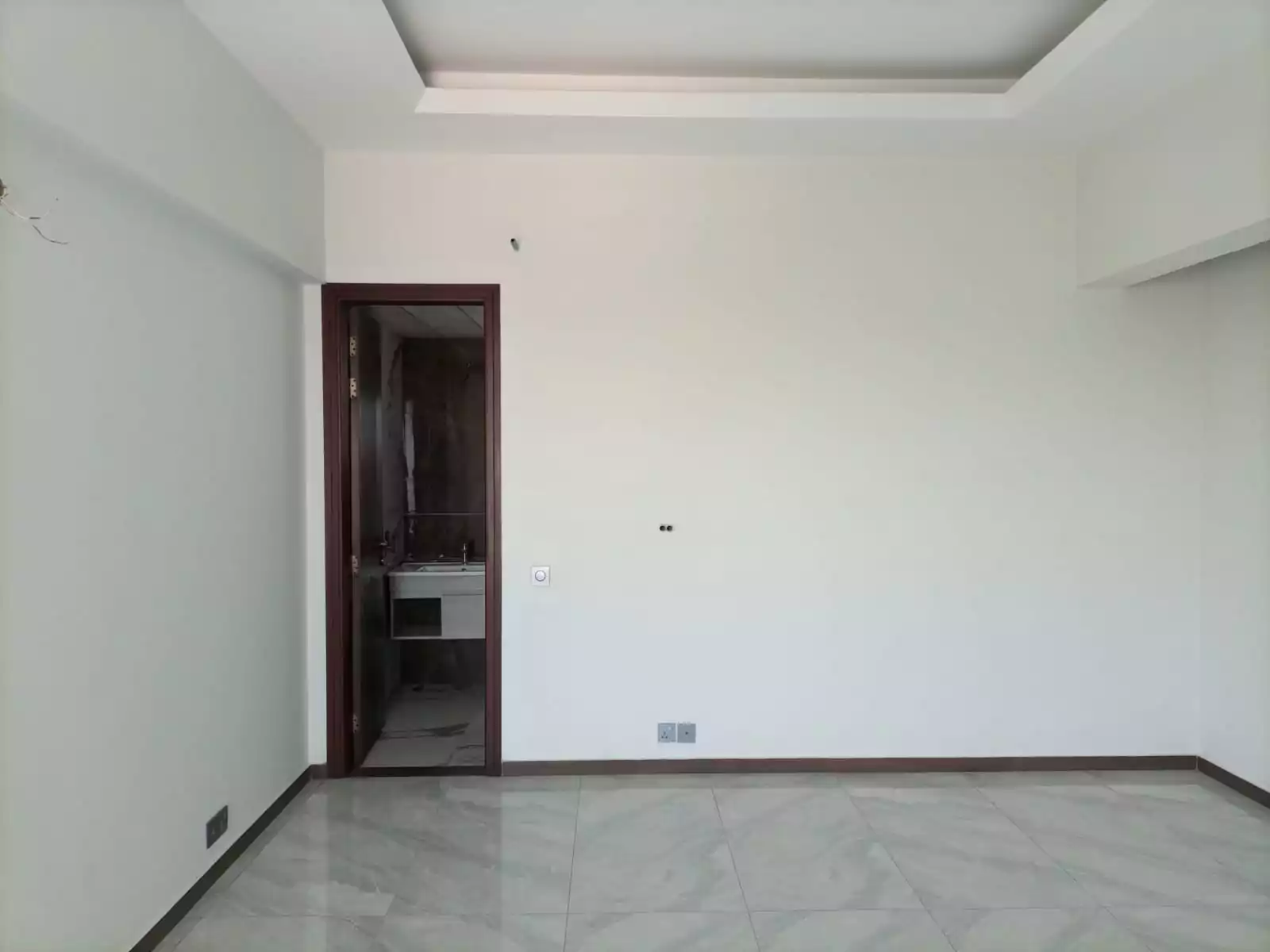 Dynasty Apartments Clifton Luxury 4-Bedroom Flats for Sale in Karachi (5) Spacious bedroom interior in Dynasty Apartments Clifton with tiled flooring, wooden door to en-suite bathroom, white walls an