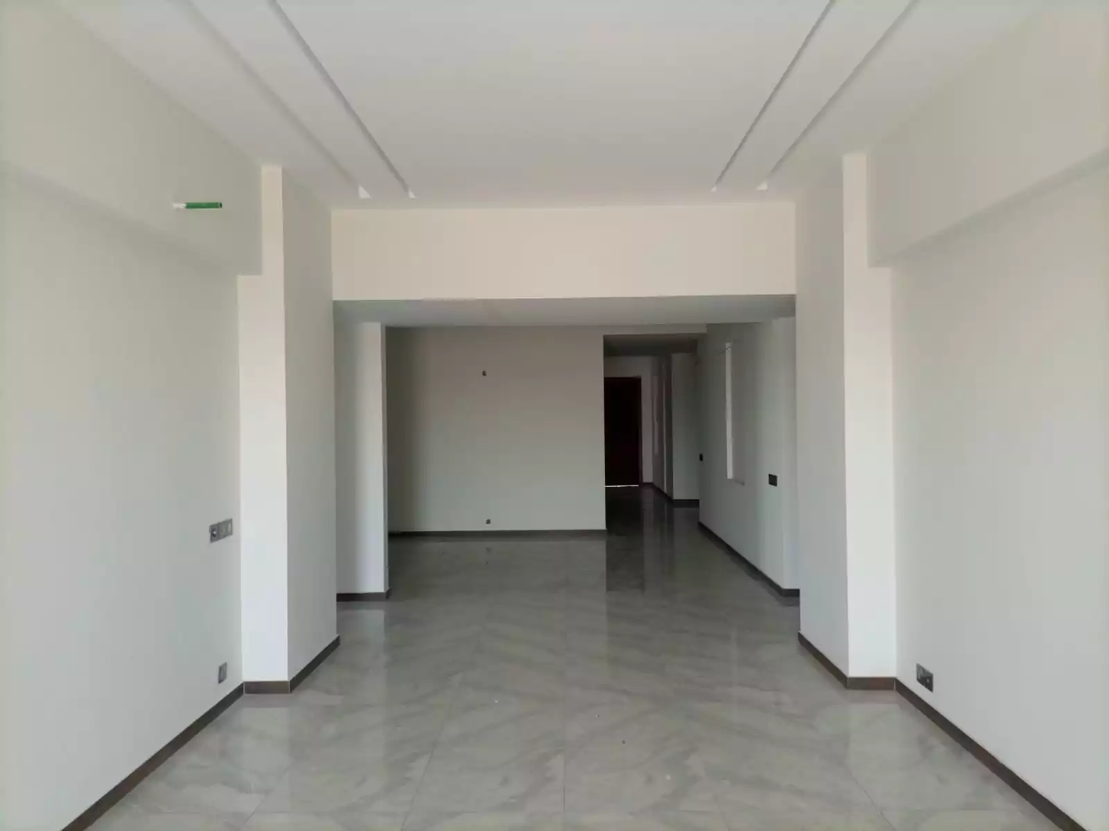Dynasty Apartments Clifton Luxury 4-Bedroom Flats for Sale in Karachi (6) Spacious open-plan interior of Dynasty Apartments Clifton luxury 4-bedroom flat with high ceilings, tiled floors, pillars, an