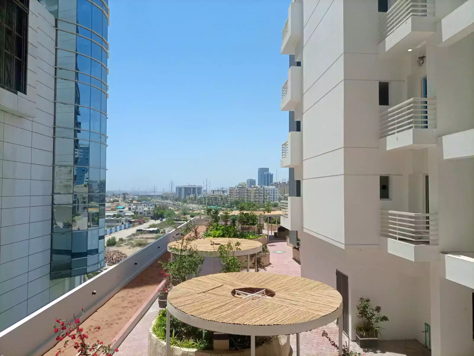 Dynasty Apartments Clifton Luxury 4-Bedroom Flats for Sale in Karachi (7) Terrace at Dynasty Apartments Clifton with shaded pergolas, planters, balconies, and city skyline views