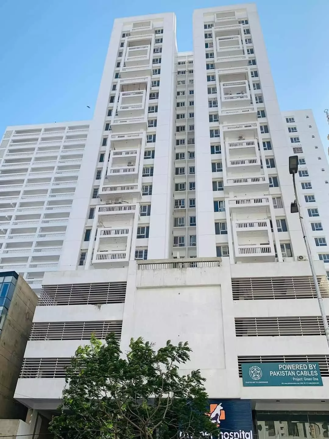 Luxurious 3-Bedroom Apartment for Sale in Green One Clifton Block 8 Karachi (1) Greens One Clifton exterior: tall white residential towers with balconies, parking garage, and surrounding greenery