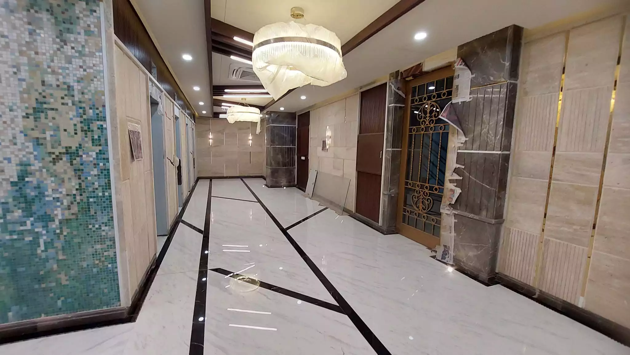 Luxurious 3-Bedroom Apartment for Sale in Green One Clifton Block 8 Karachi (10) Elegant corridor with marble flooring, mosaic tiled walls, elevators, ornate doors and chandeliers in Greens One Clifton 3-be