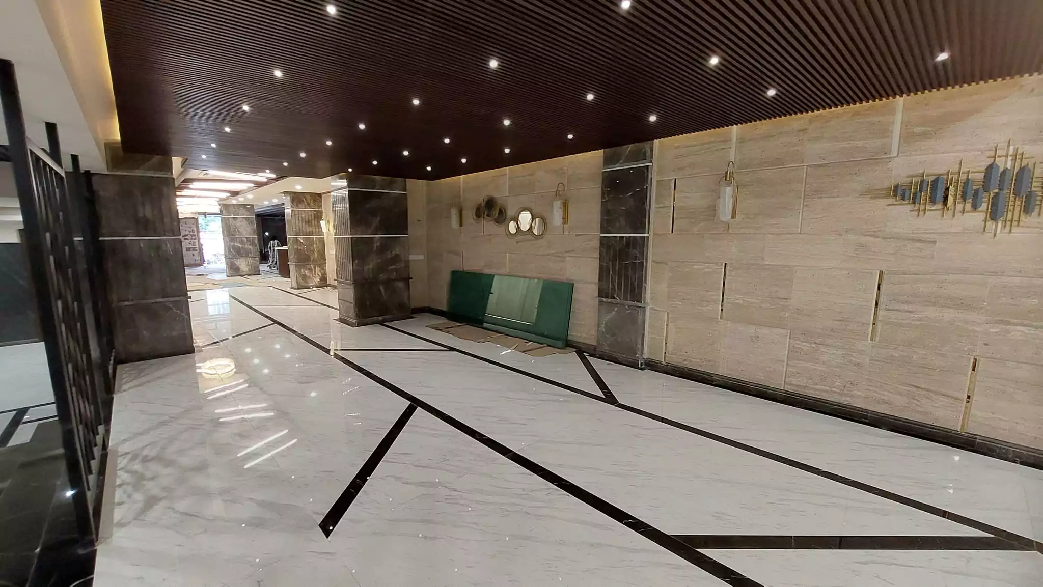 Luxurious 3-Bedroom Apartment for Sale in Green One Clifton Block 8 Karachi (12) Elegant corridor in Greens One Clifton with wooden slat ceiling, veined marble floors, stone walls, metallic art, and green b