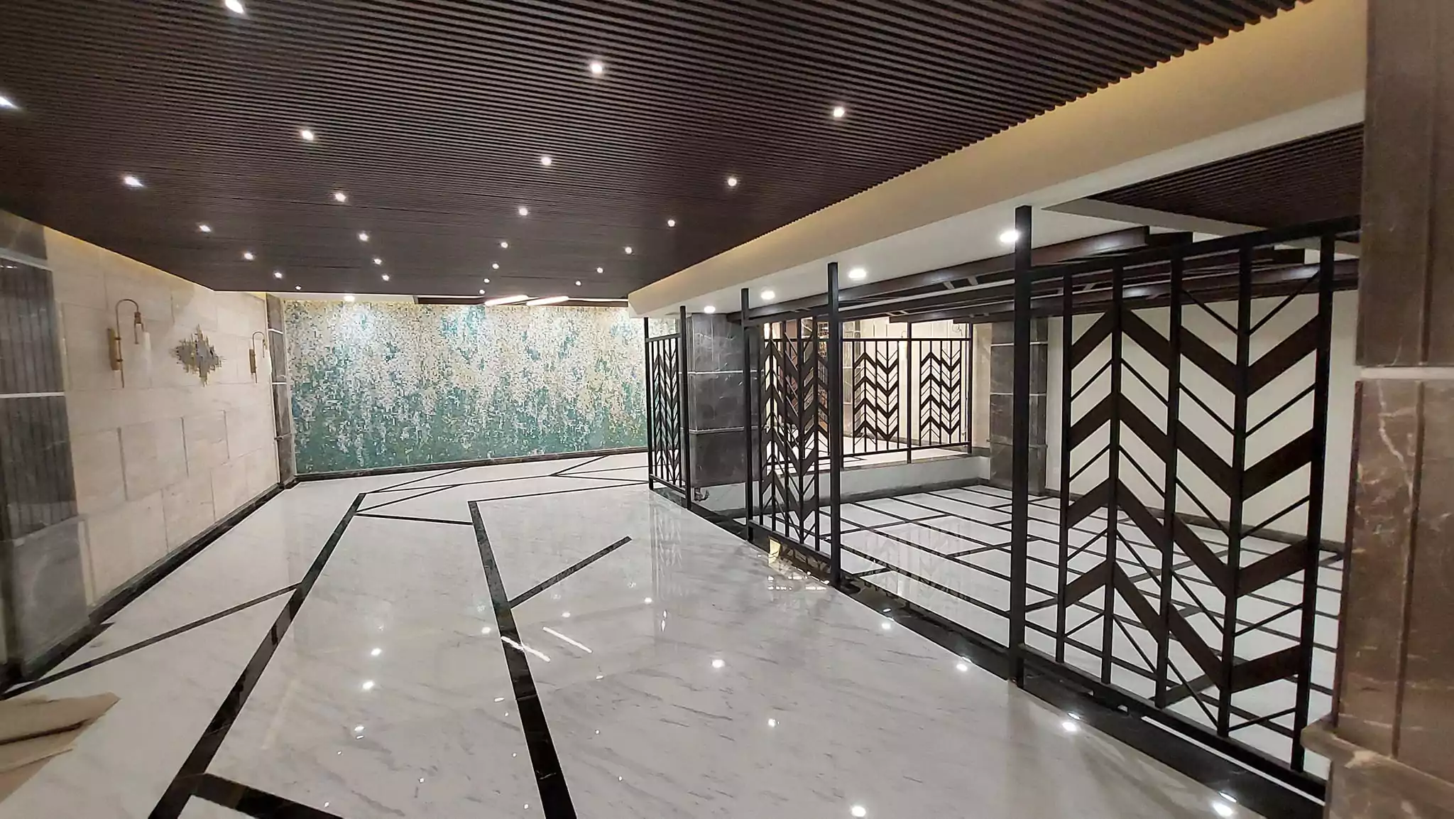 Luxurious 3-Bedroom Apartment for Sale in Green One Clifton Block 8 Karachi (8) Elegant lobby in Greens One Clifton with wooden ceiling, marble floors, green mosaic wall, and black metal partitions