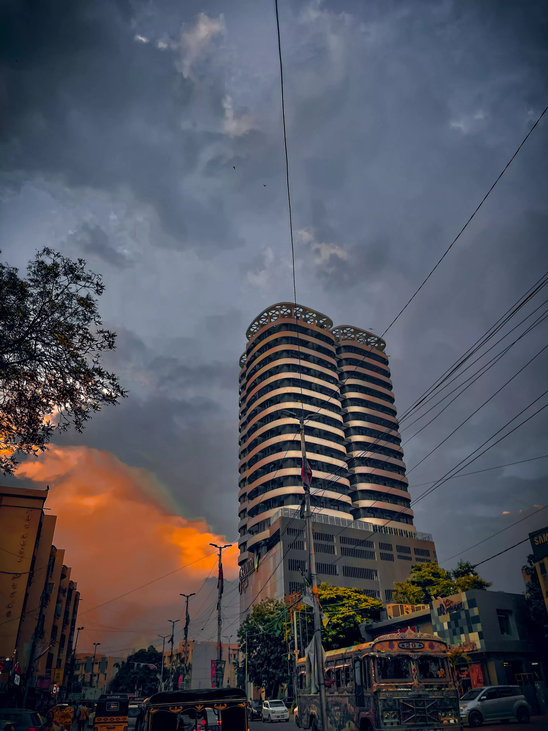 Luxurious 1800 Sqft Flat for Rent in Country 8 Clifton Block 8 Karachi (4) Curved twin towers of Country 8 Clifton high-rise under dramatic cloudy sky with street traffic and trees