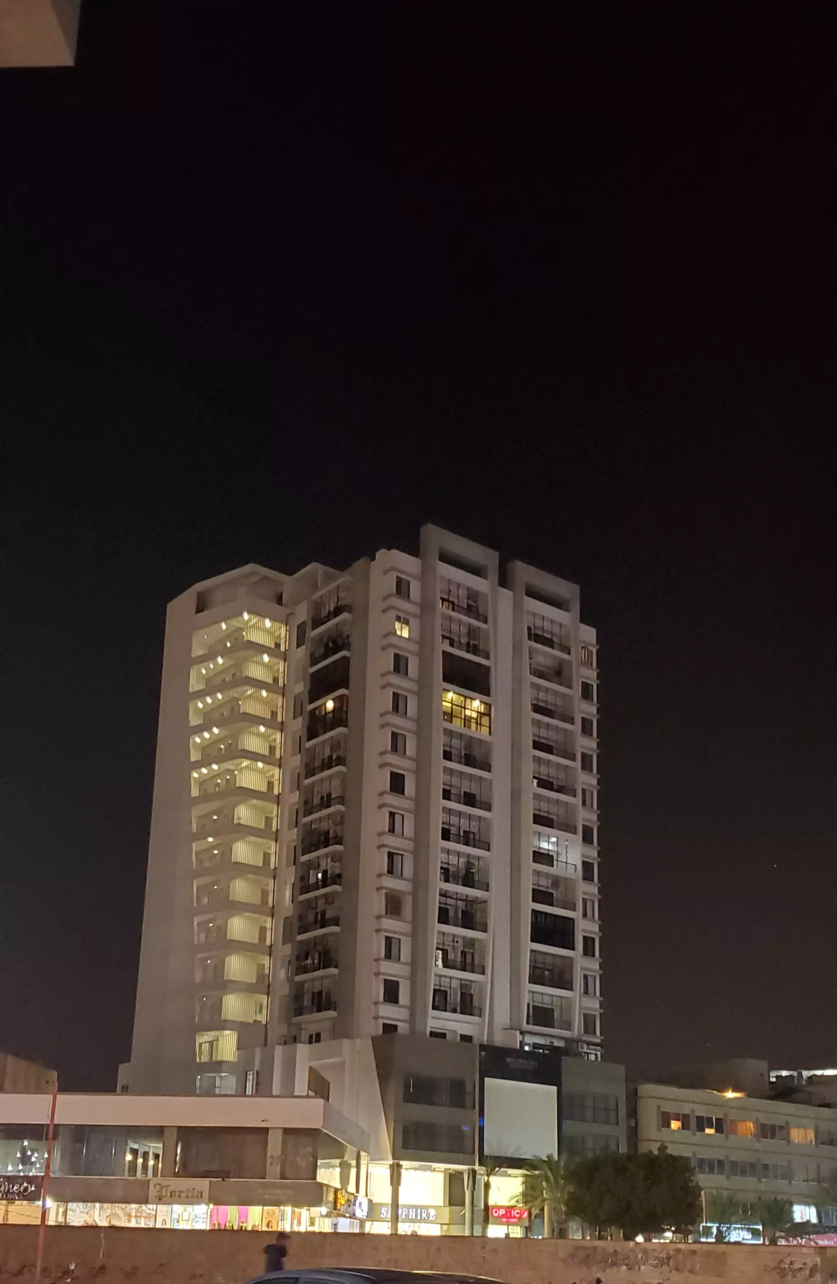 Luxurious Flat for Sale in Machiyara Tower Block 8 Clifton Karachi (5) Night view of Machiyara Tower in Clifton, modern high-rise with white facade and illuminated upper floors