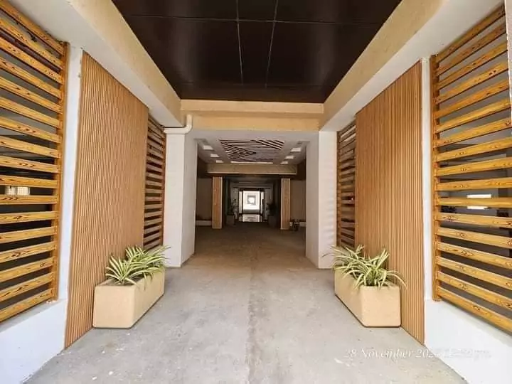 Luxurious 3 Bedroom Flat for Rent in Askari 5, Sector J Malir Cantonment Karachi (4) Elegant entrance hallway with wooden slat walls, potted plants in white pots, black grid ceiling, and polished floor in 3-bed