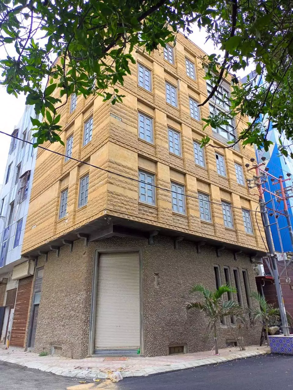Beige multi-story commercial building for rent in DHA Phase 6 Karachi, corner location with textured facade, large windows, a