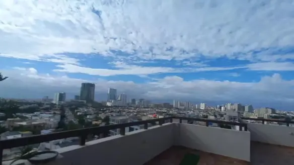Panoramic Balcony View Of City Skyline With High-Rise Buildings, Urban Neighborhoods, And Partly Cloudy Tropical Sky