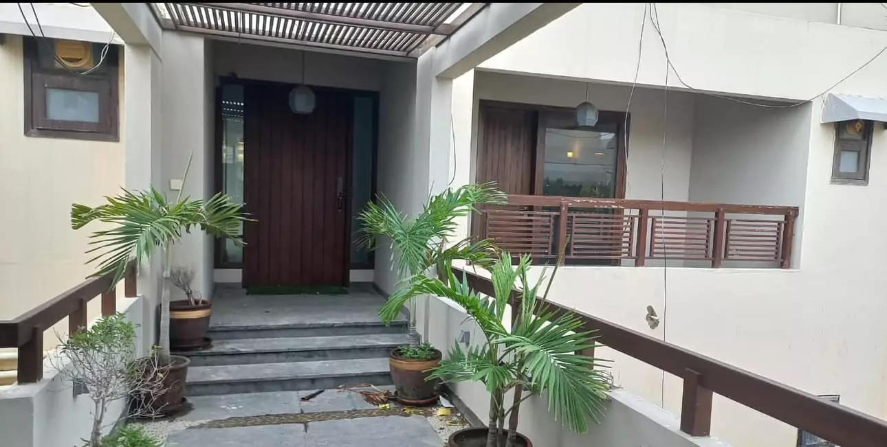 Luxurious 5-Bed Penthouse for Rent in Mall Square Zamzam – DHA Phase 5 Karachi (5) Grand wooden entrance door to 5-bed penthouse in Mall Square DHA, with potted palms, modern pergola, steps, and beige balcony